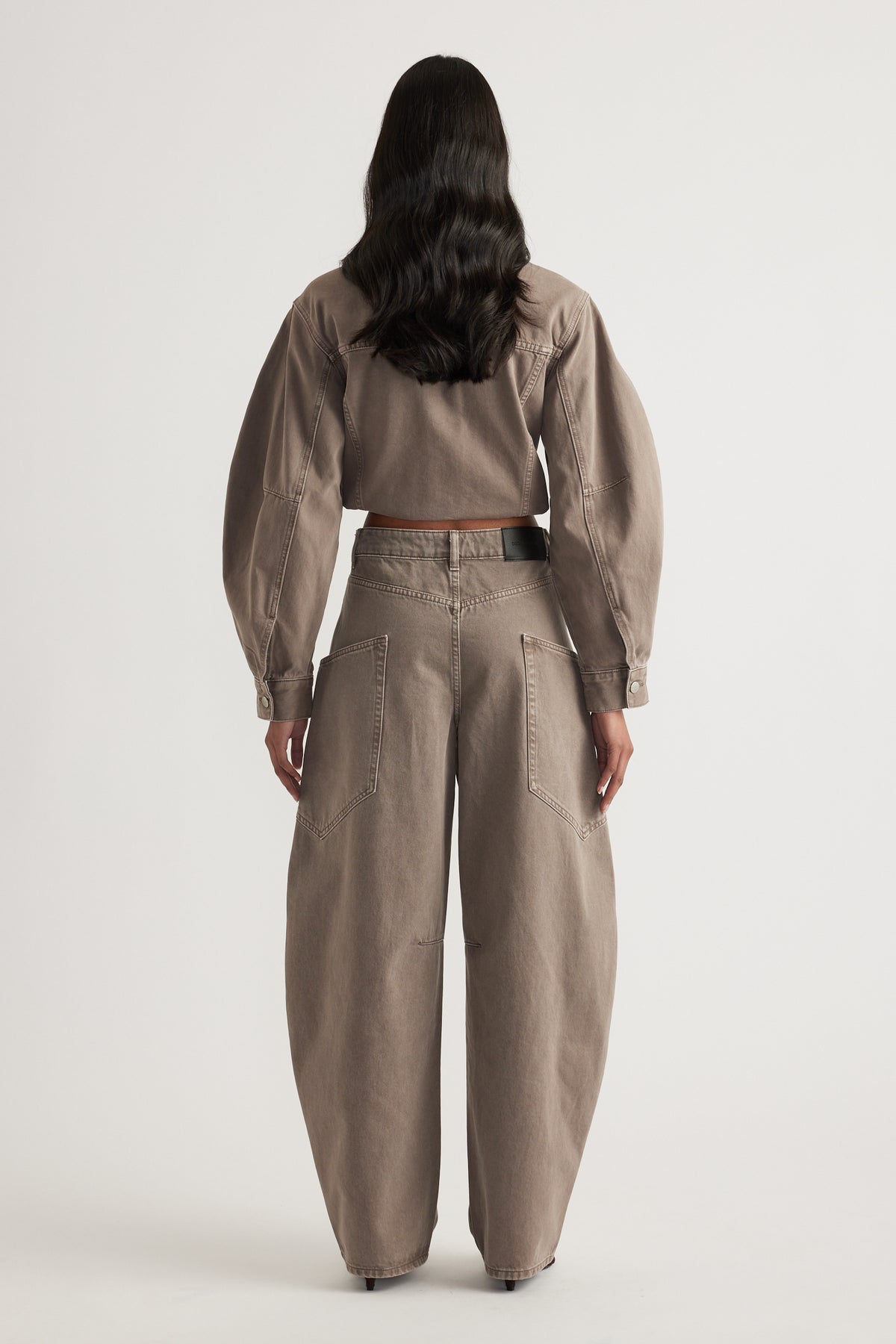 Woman wearing taupe cargo barrel leg jeans with back pockets and a matching cropped denim jacket