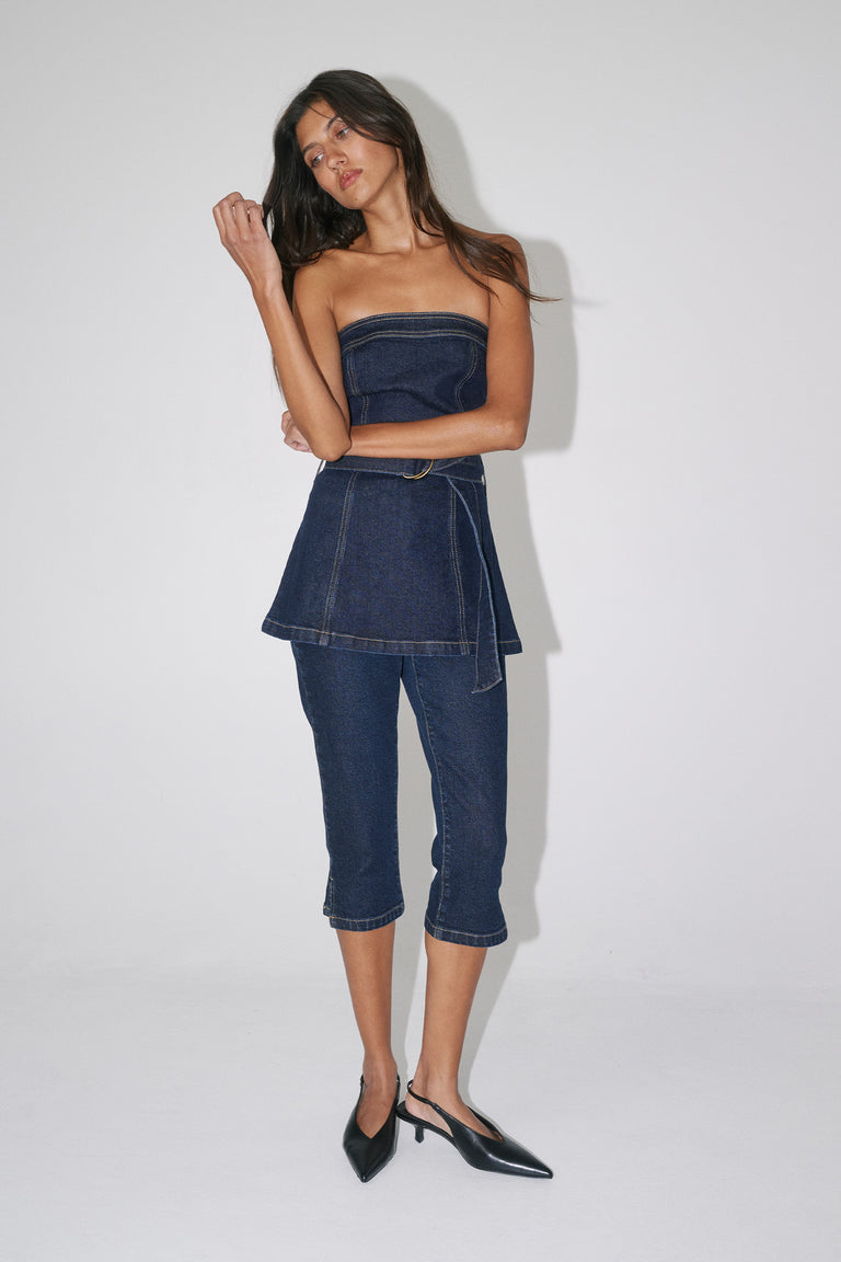 Model wearing a strapless dark denim top with matching capri jeans and black pointed heels
