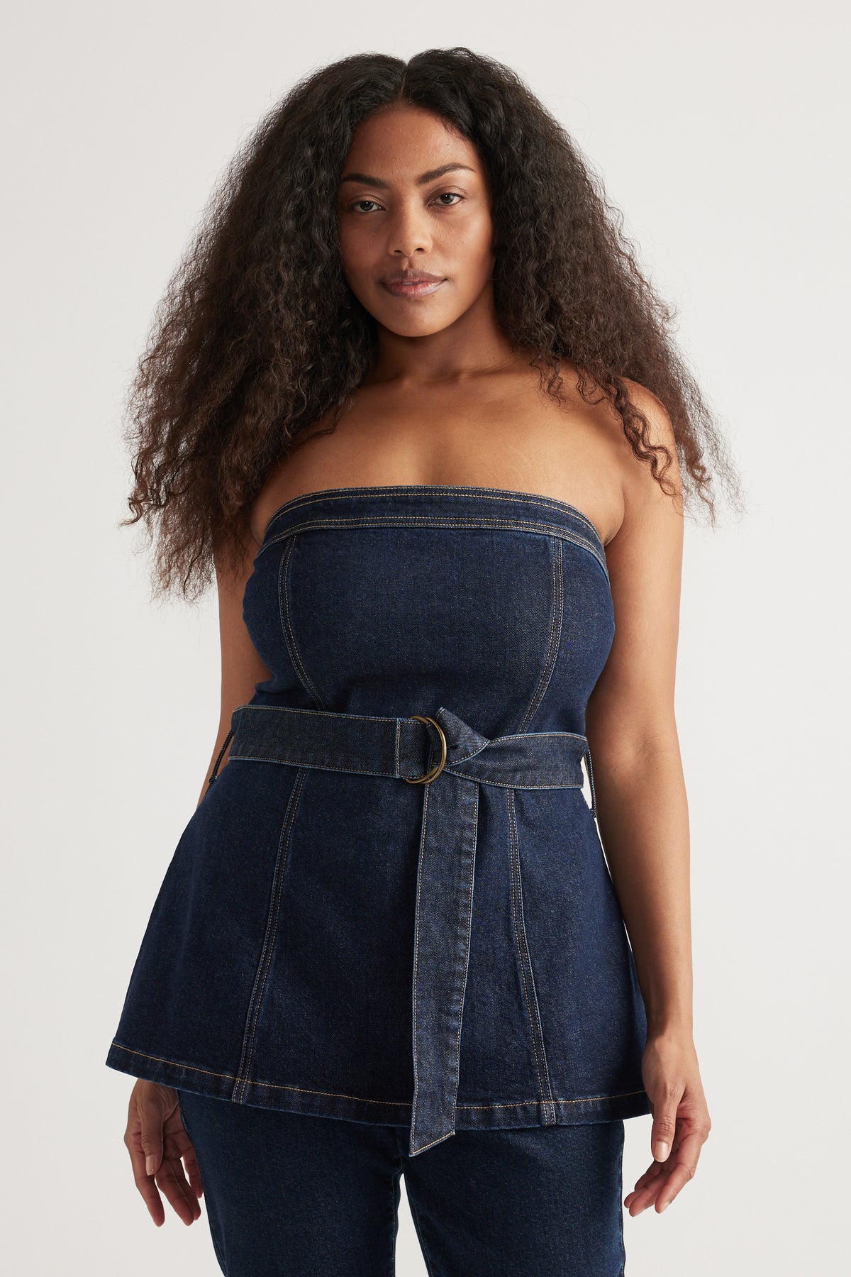Model wearing a strapless dark denim top with a belted waist and matching jeans