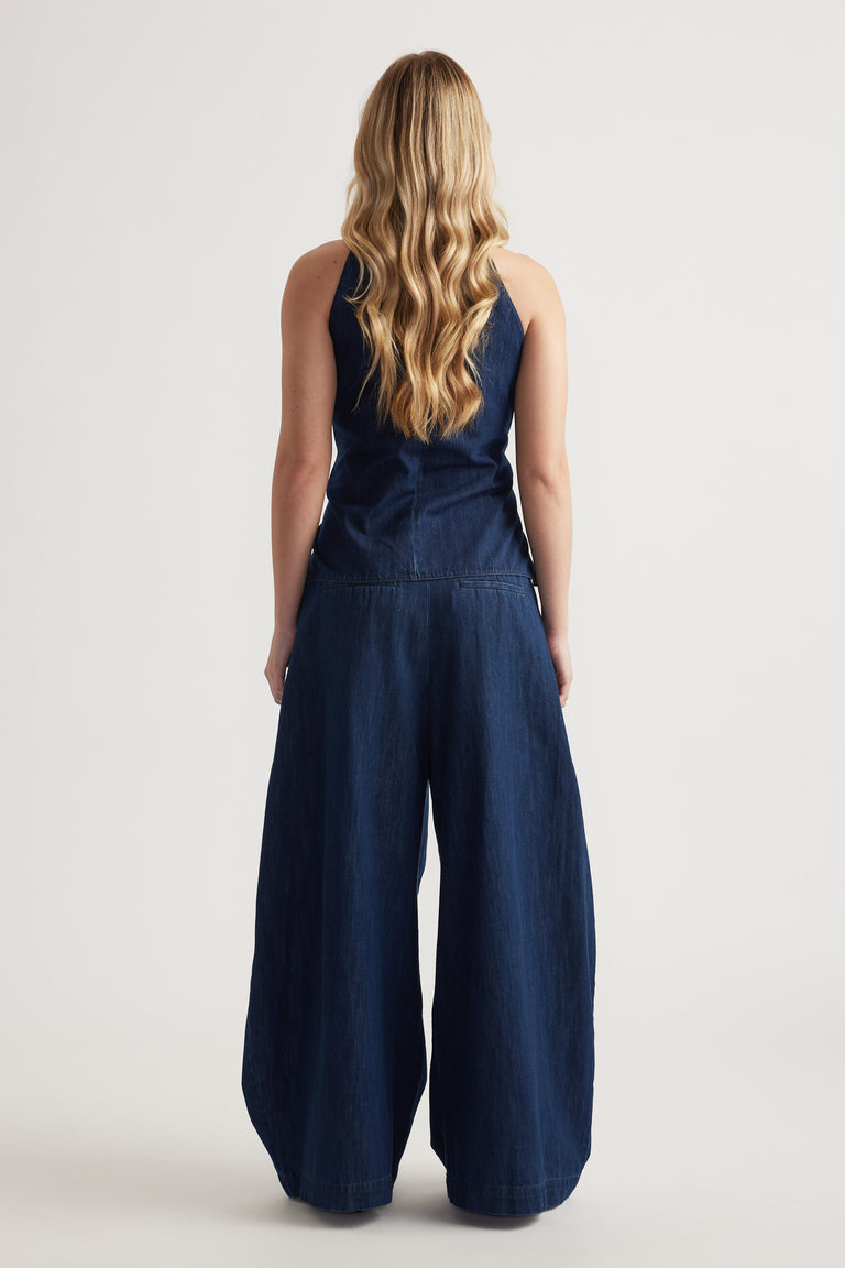Back view of a woman wearing a navy sleeveless top with wide-leg denim pants