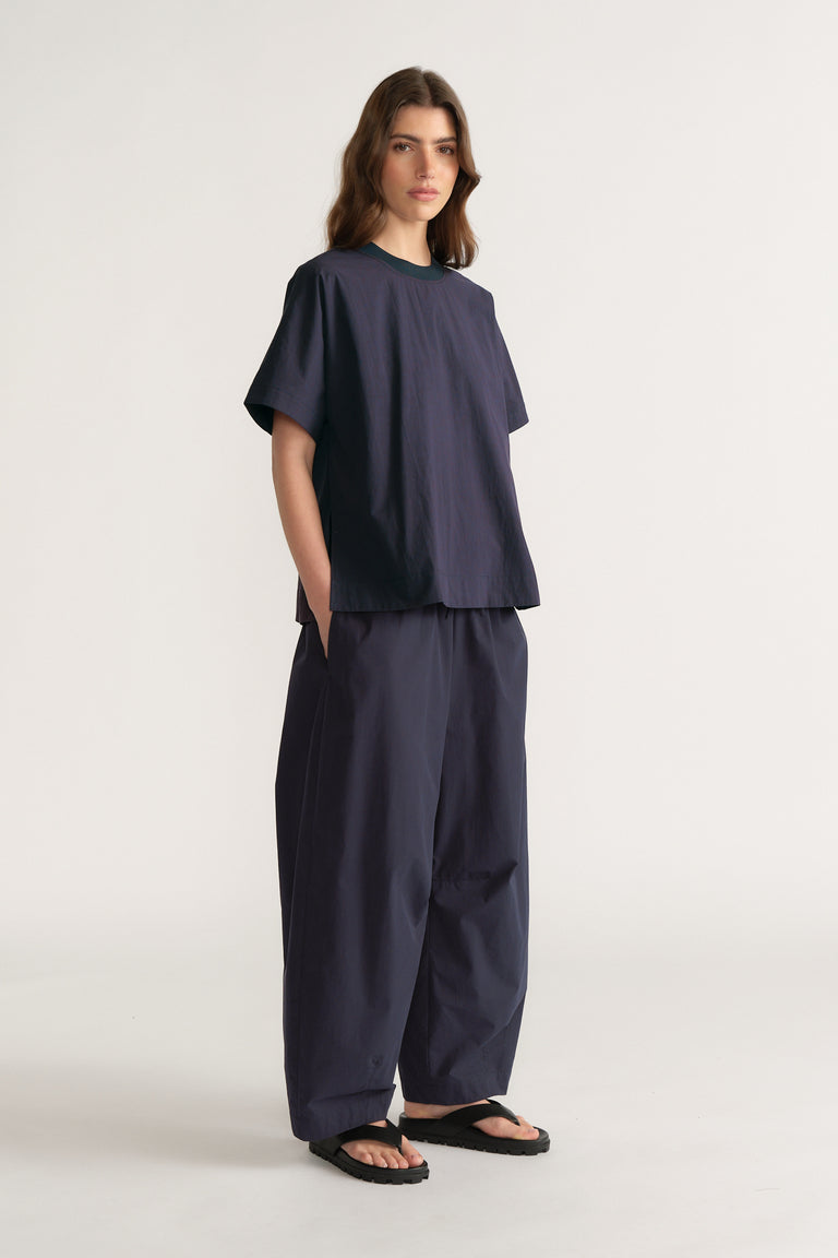 Woman in a relaxed navy boxy top with matching wide leg pants and black sandals