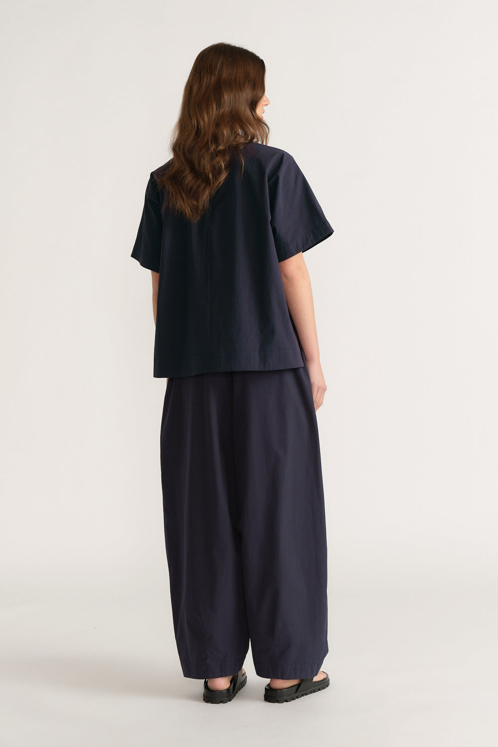 Woman viewed from behind wearing a navy oversized short sleeve top with wide leg pants