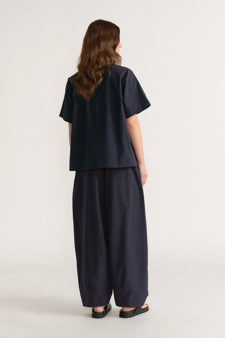 Woman viewed from behind wearing a navy oversized short sleeve top with wide leg pants