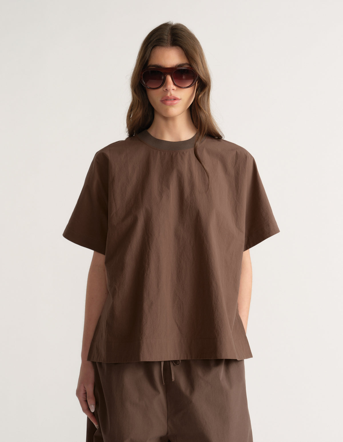 Woman wearing a brown oversized short sleeve top with matching pants and sunglasses