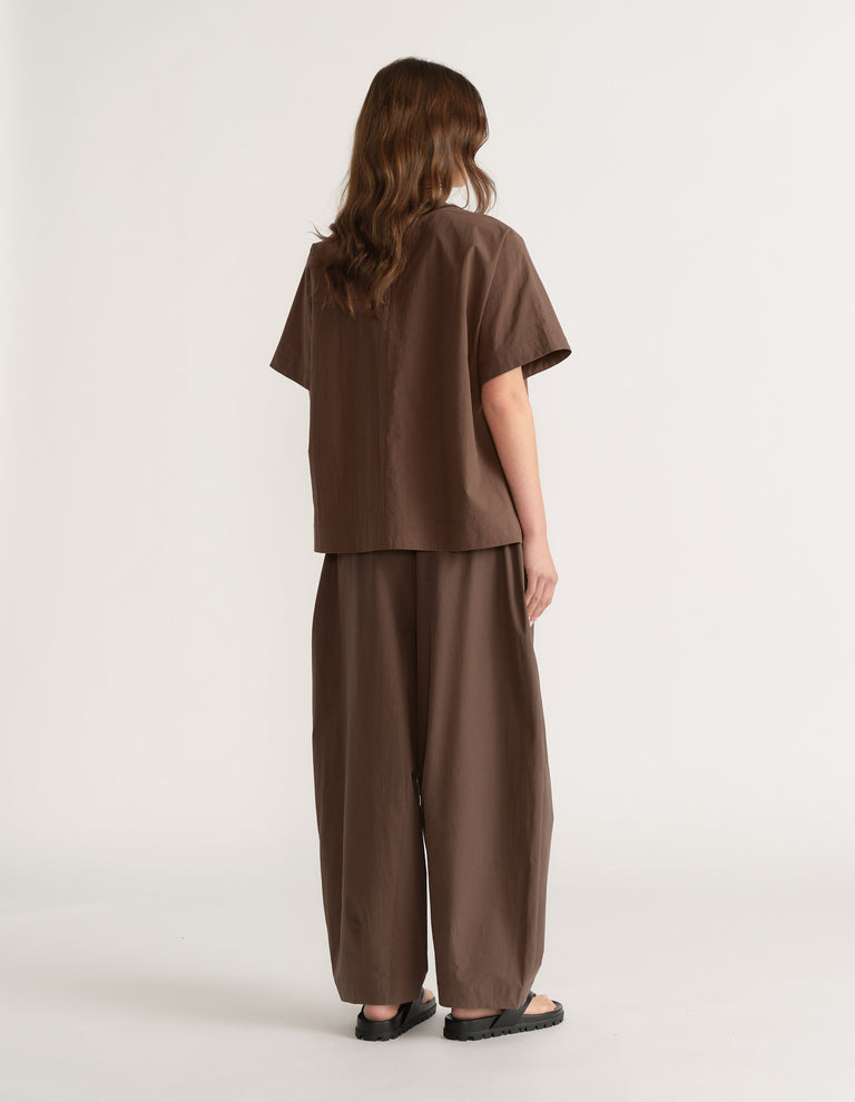 Woman wearing a chocolate brown oversized short sleeve top with matching wide leg pants and sandals