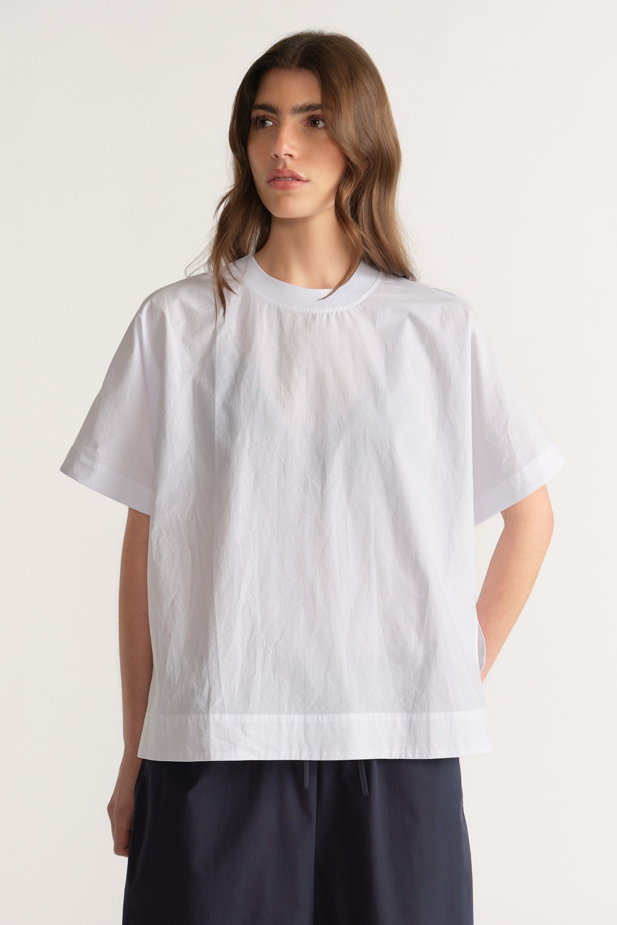 Woman in a white oversized crew neck top with short sleeves and black pants
