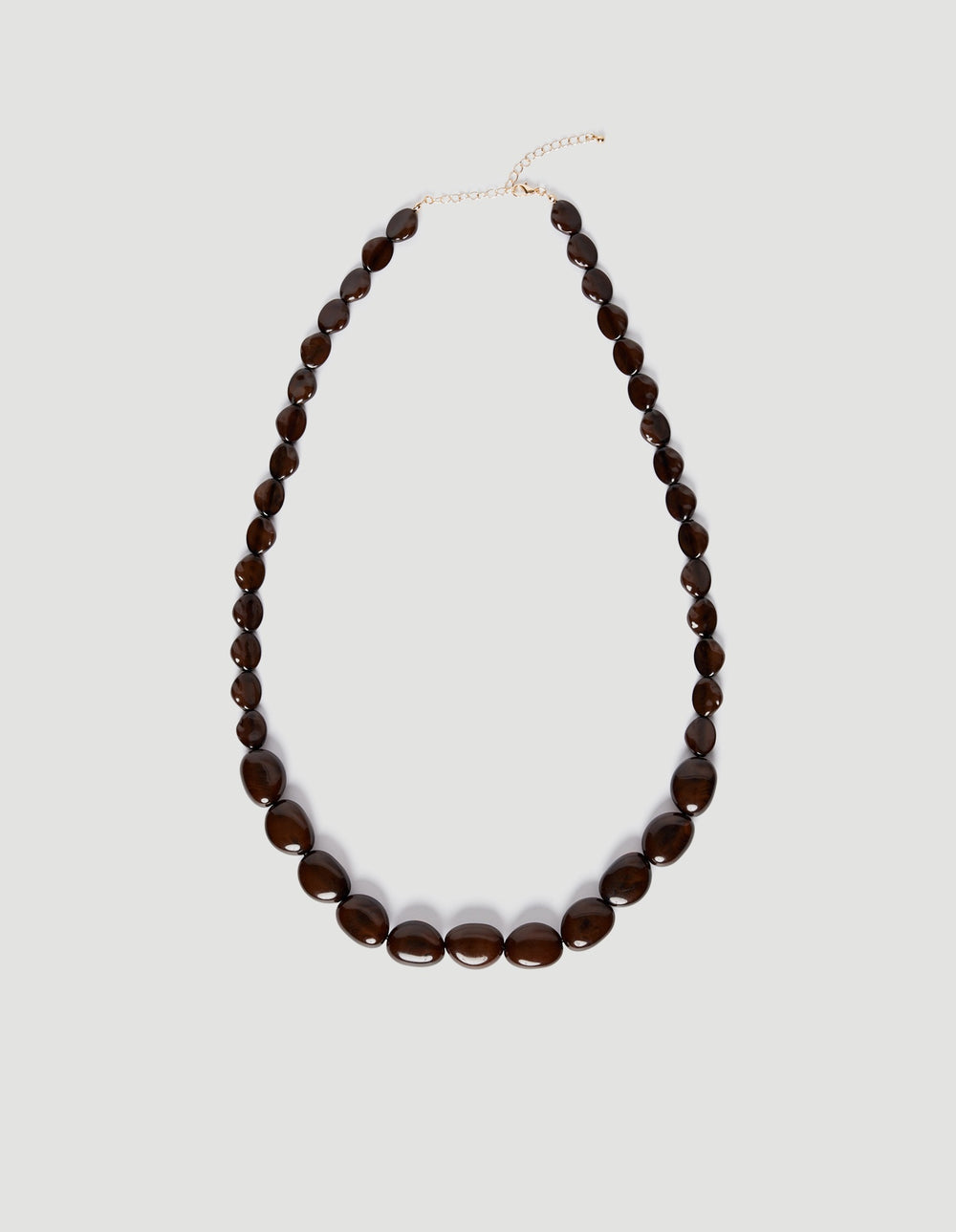 Long statement necklace featuring multi-sized dark resin beads with an adjustable gold-tone extension chain