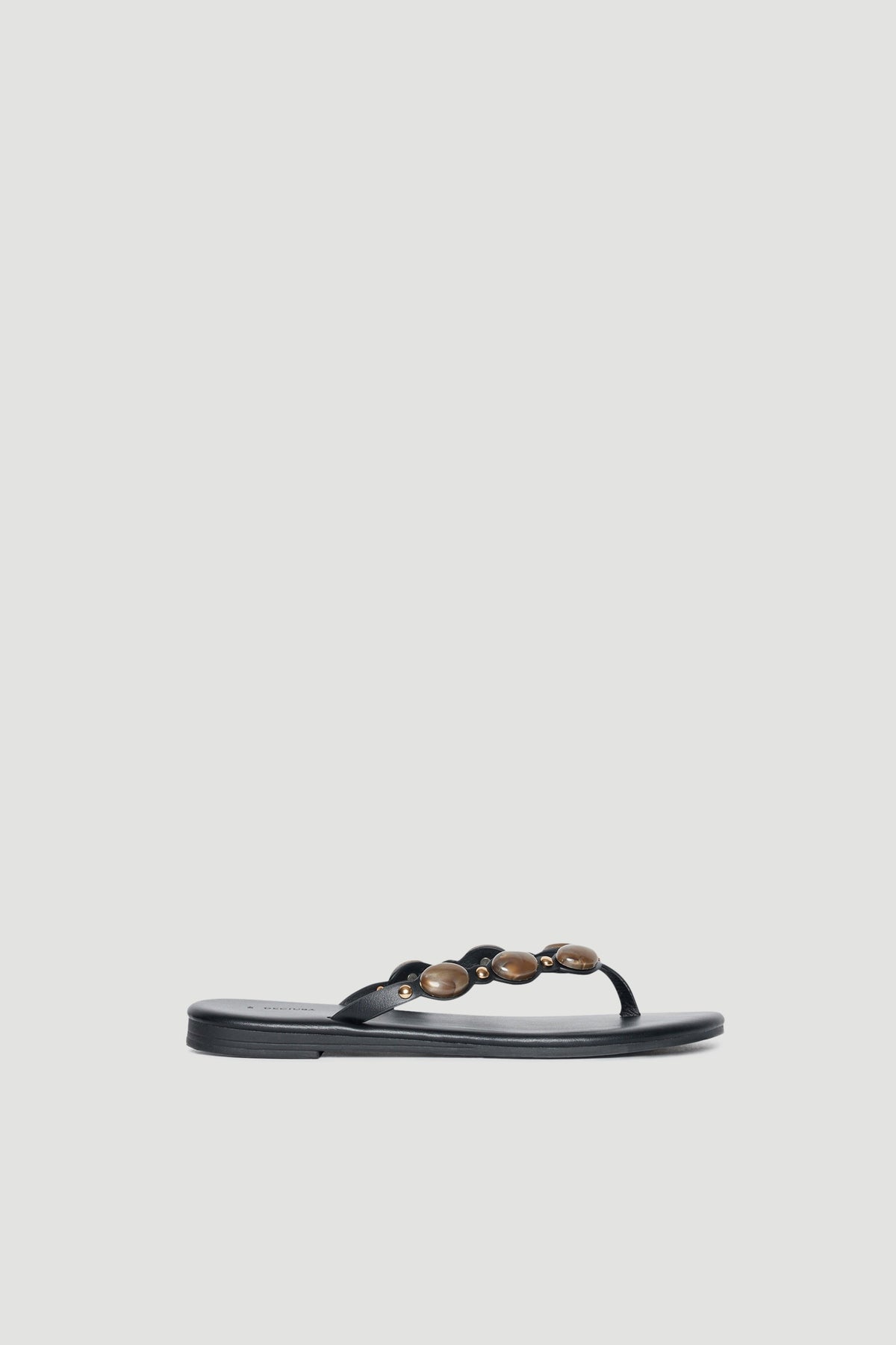 Black thong sandal with rounded gemstone embellishments across the strap and a flat footbed
