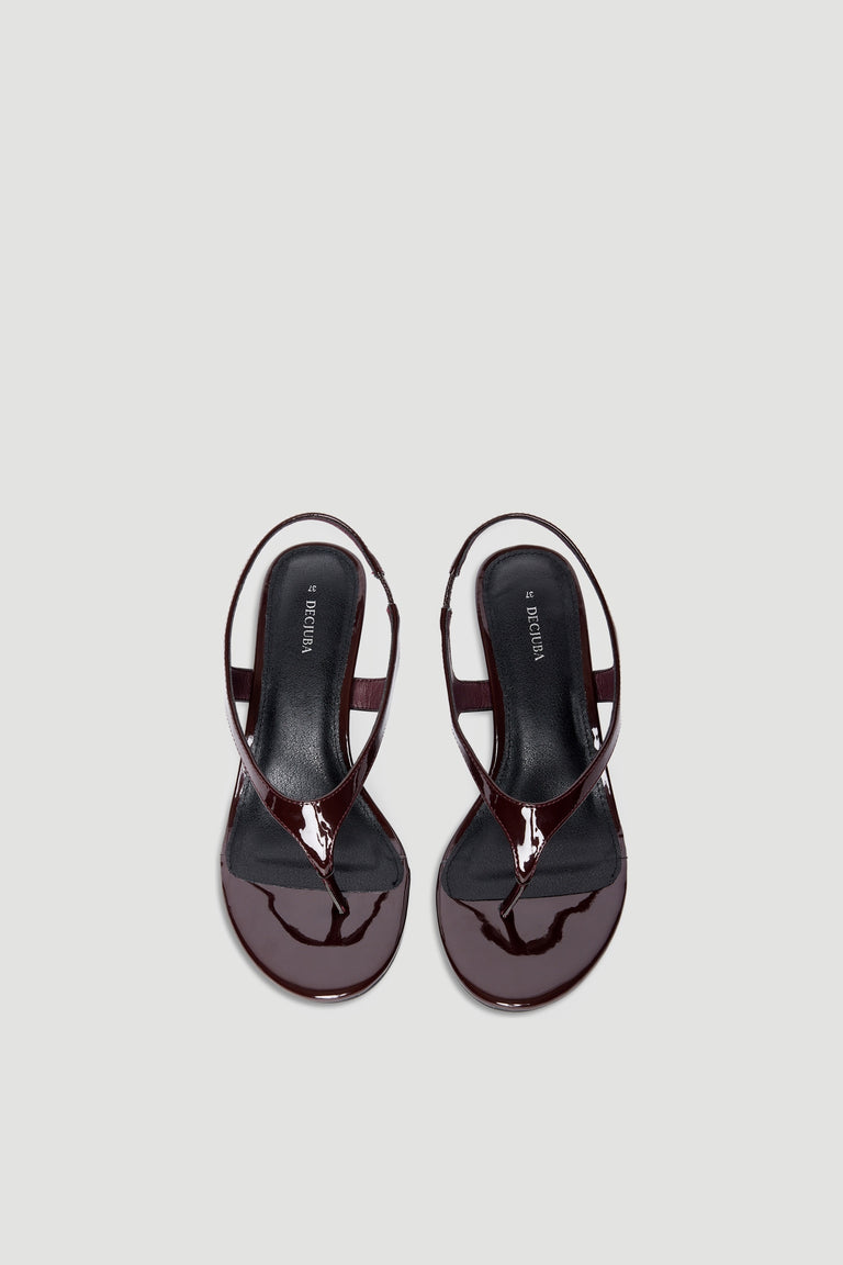 Glossy dark brown patent thong sandals with slingback strap and square toe on a light neutral background