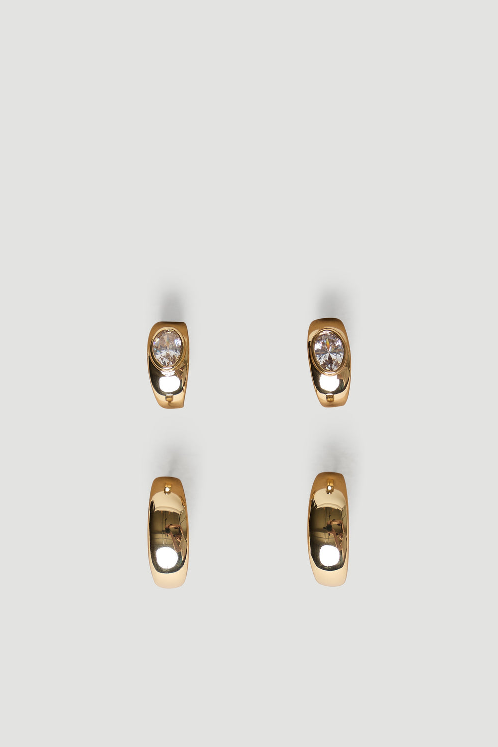 Pair of polished gold chunky hoop earrings with smooth finish, one set featuring sparkling clear stones for subtle shine.