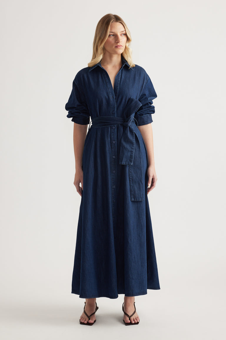Woman in a dark denim midi shirt dress with rolled sleeves, collar and adjustable waist tie