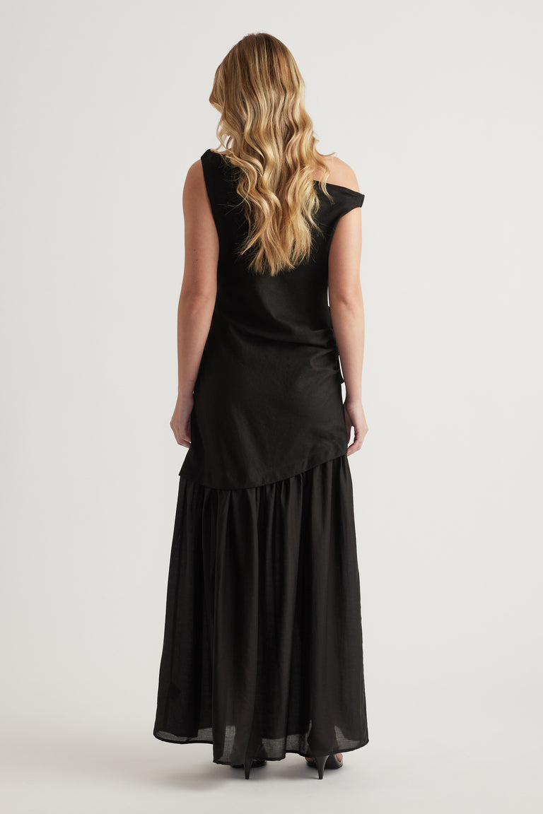Woman wearing a black off shoulder maxi dress with a flowing A line skirt from behind