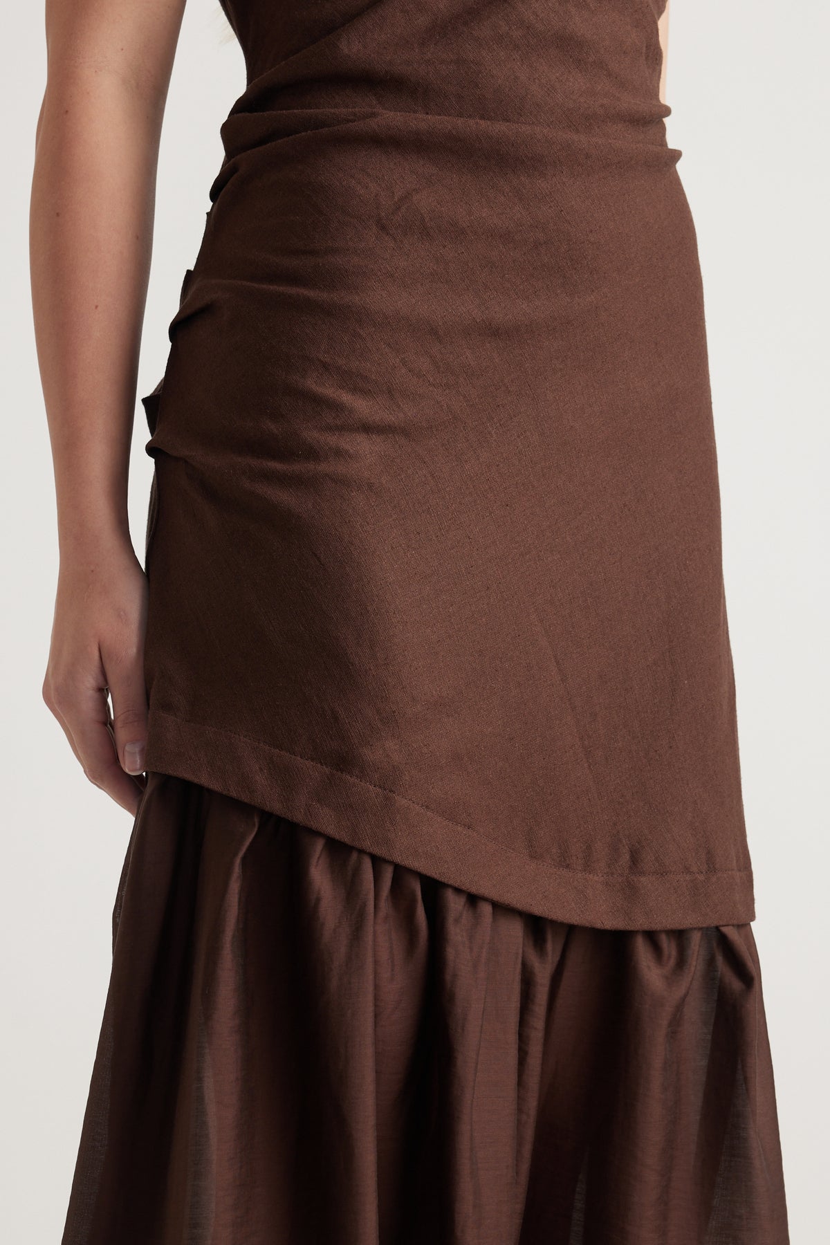 Woman wearing a brown spliced maxi dress with a draped asymmetric skirt