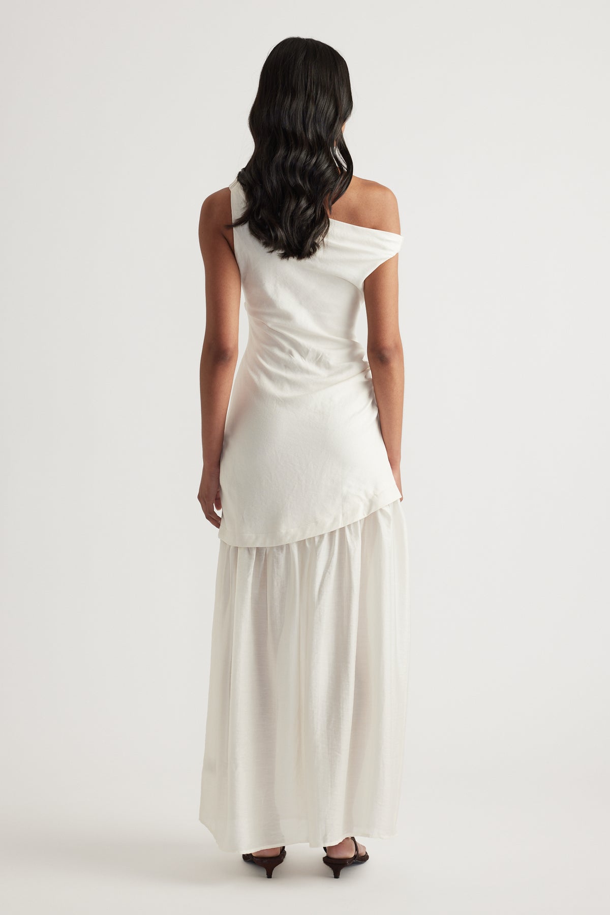 Woman wearing an ivory off shoulder spliced maxi dress with a draped finish, viewed from behind