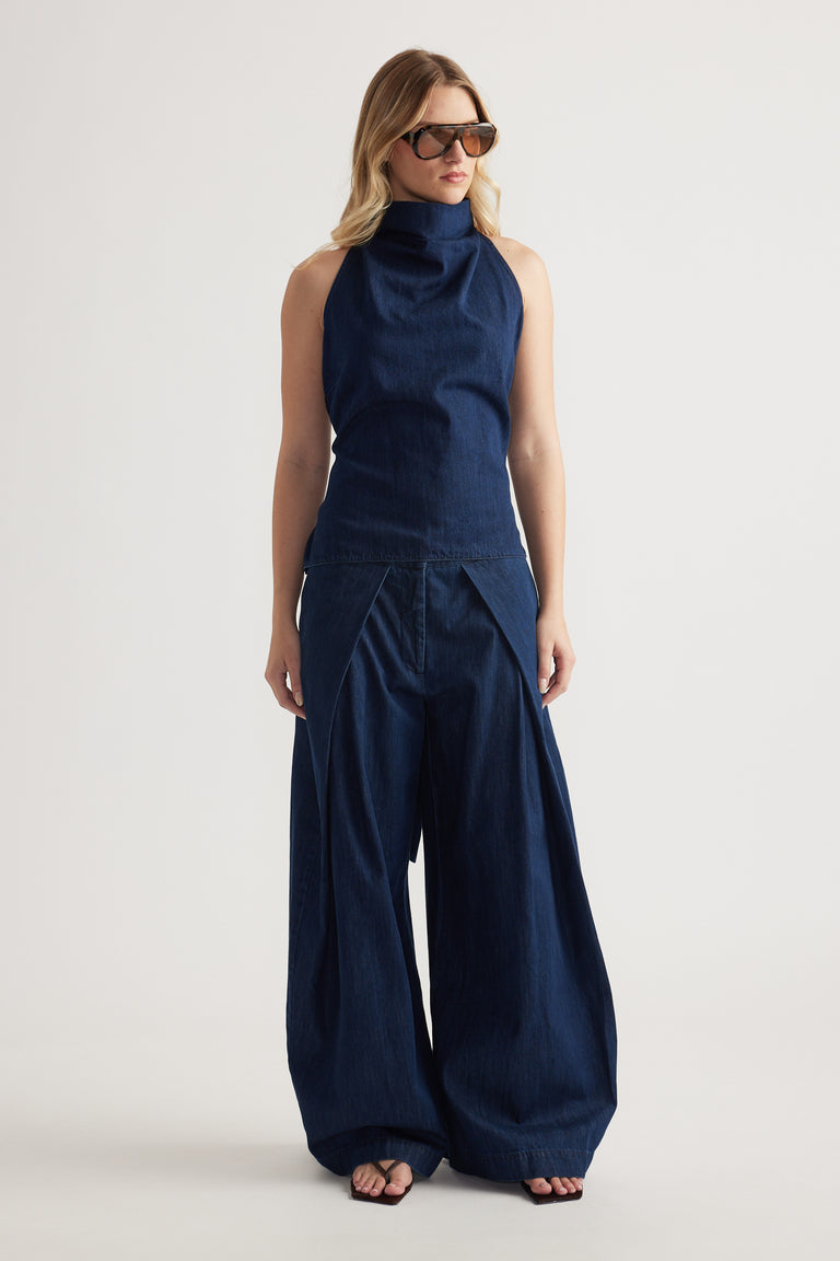 Woman wearing navy wide leg denim pants with a sleeveless high neck top and sunglasses