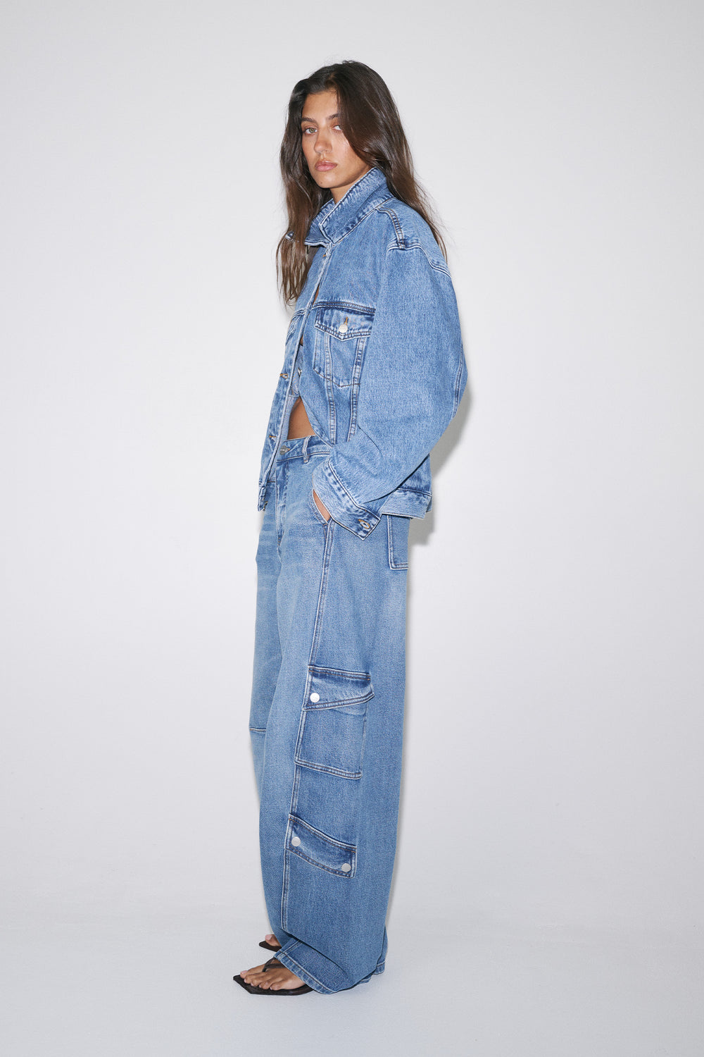 Woman wearing high-rise blue cargo barrel jeans with utility pockets and a relaxed denim jacket