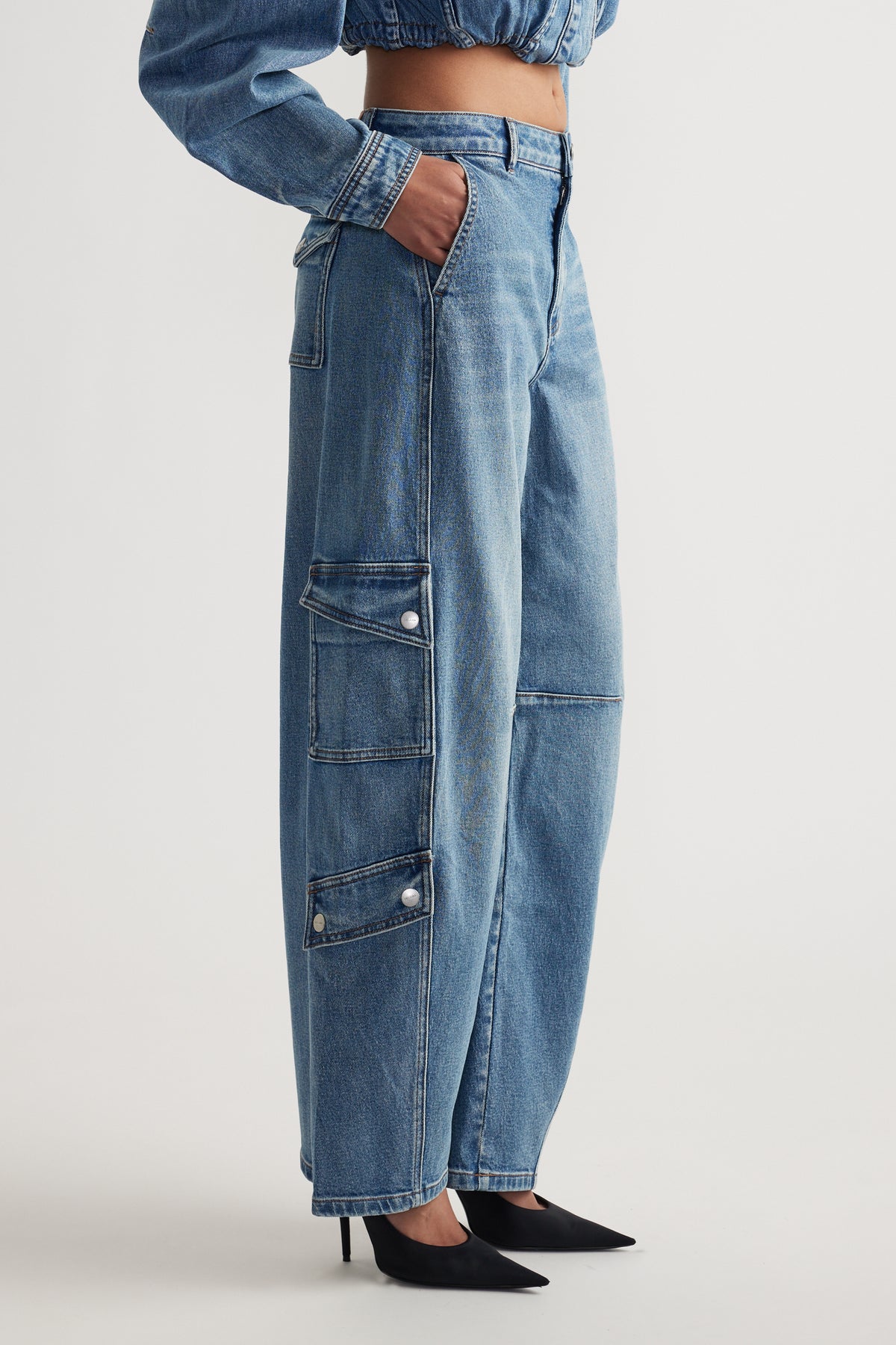 Light wash denim barrel-leg jeans with cargo pockets styled with black pointed heels and a cropped top