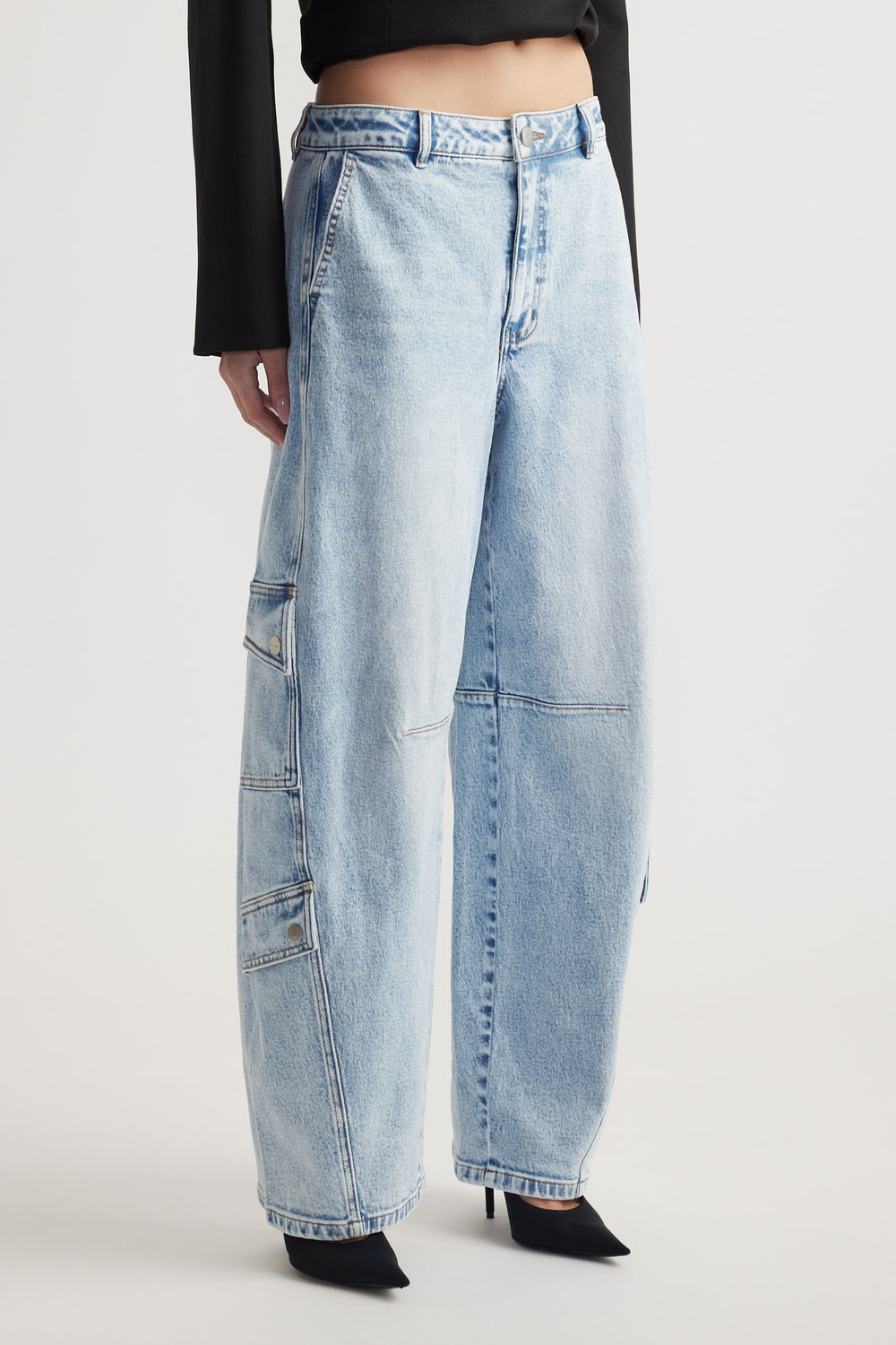 Light wash wide-leg denim jeans with cargo pockets and stitched panel details paired with black pointed heels