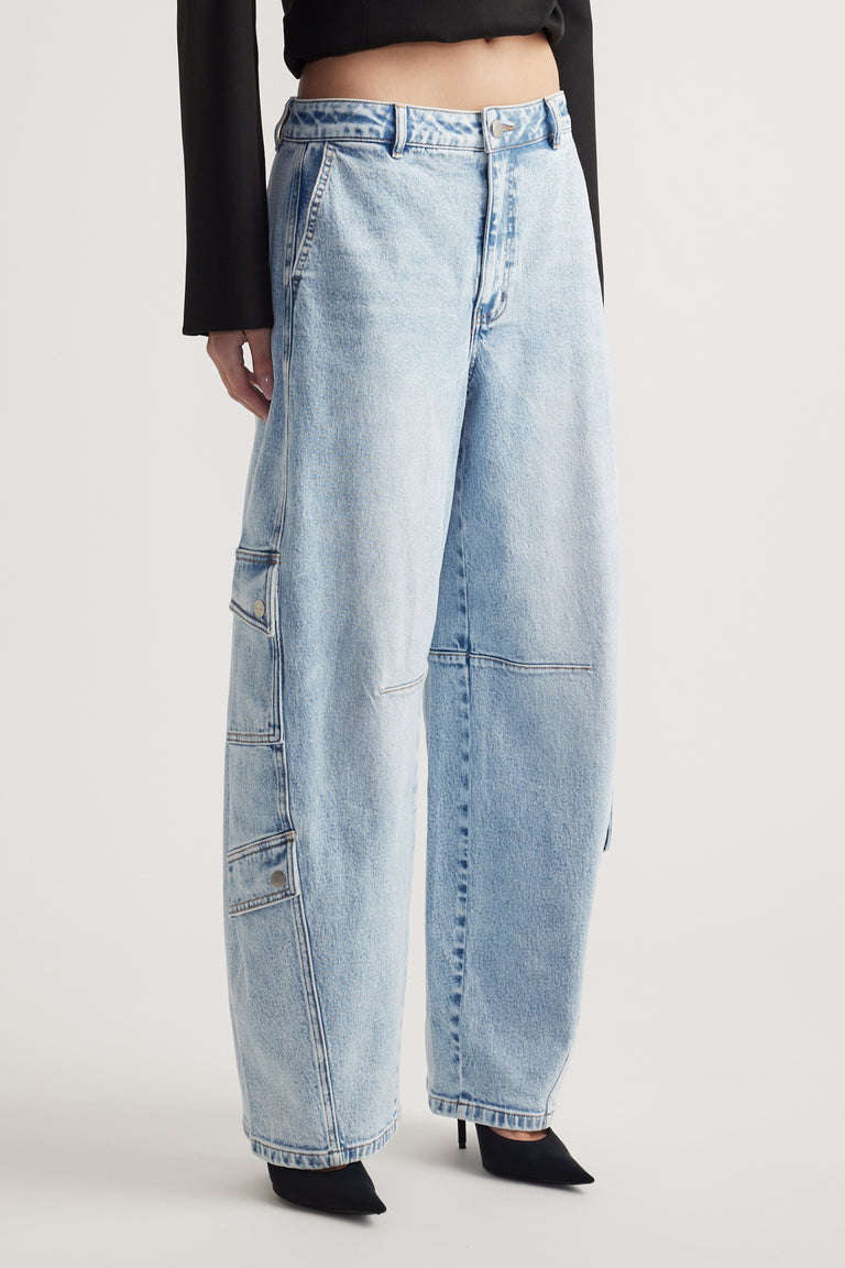 Light wash wide-leg denim jeans with cargo pockets and stitched panel details paired with black pointed heels