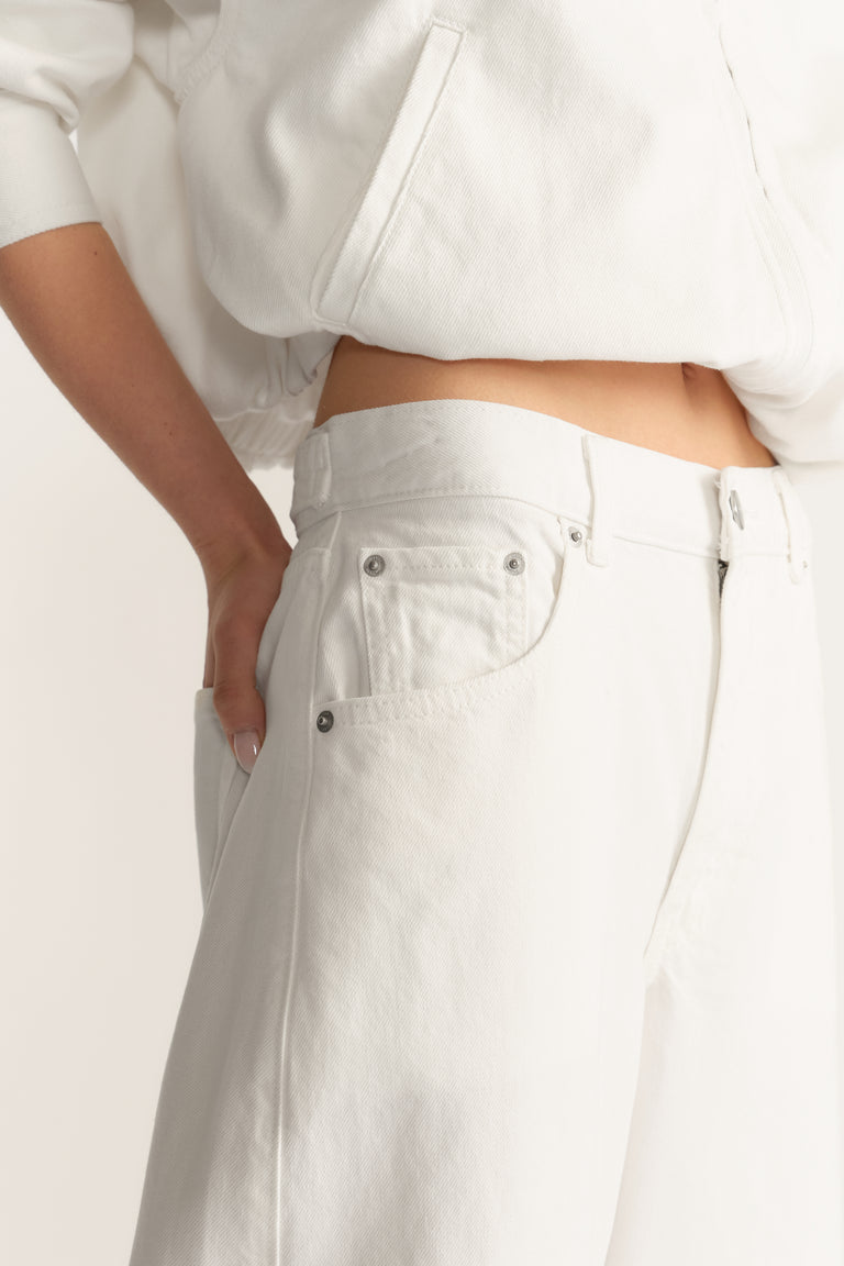 Woman wearing white barrel-leg jeans with a cropped white sweatshirt and side pockets
