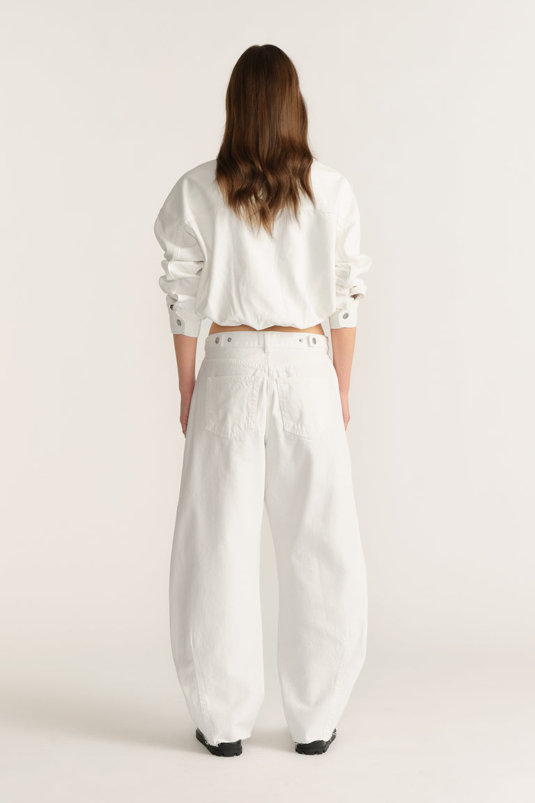 Woman wearing white barrel-leg jeans with a cinched waist and cropped long-sleeve top, viewed from behind