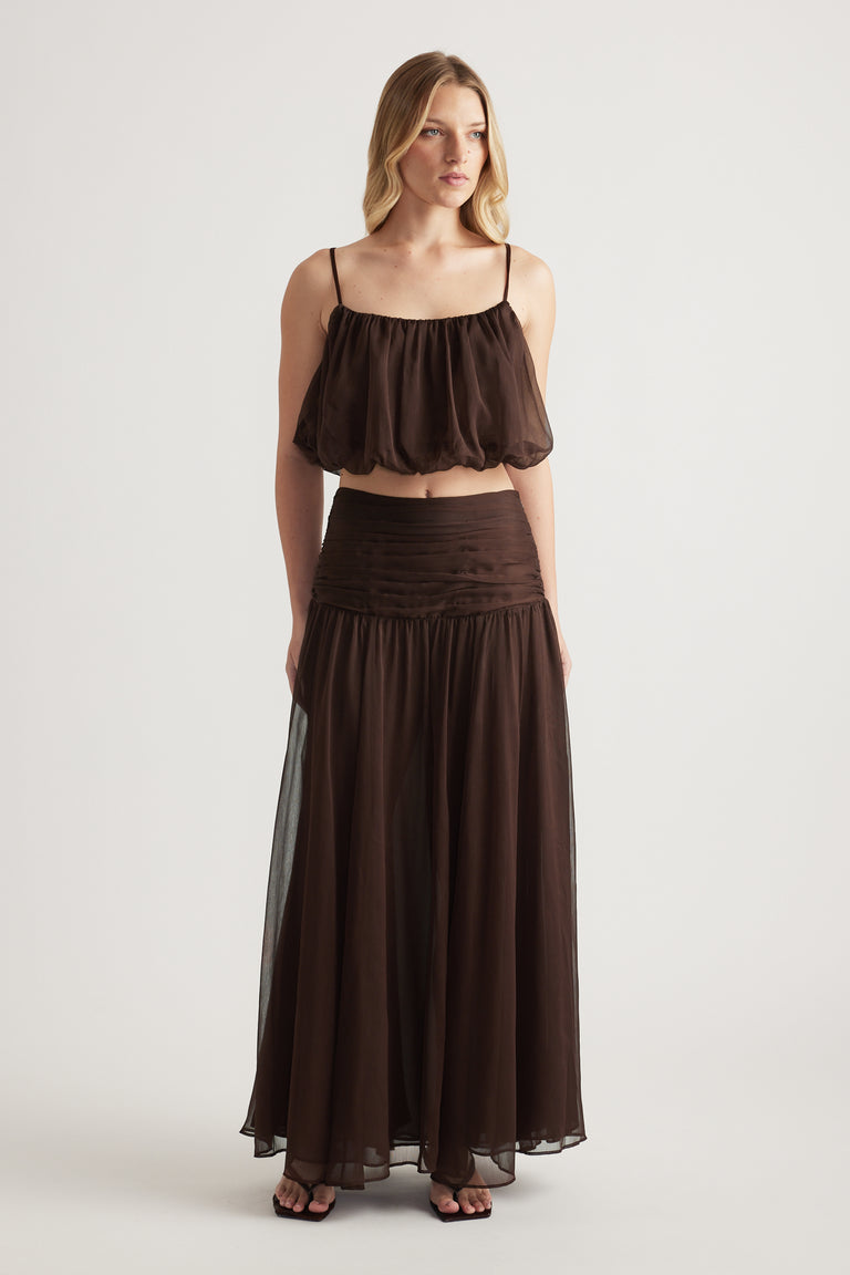 Woman wearing a brown cropped cami with thin straps and a matching flowing maxi skirt