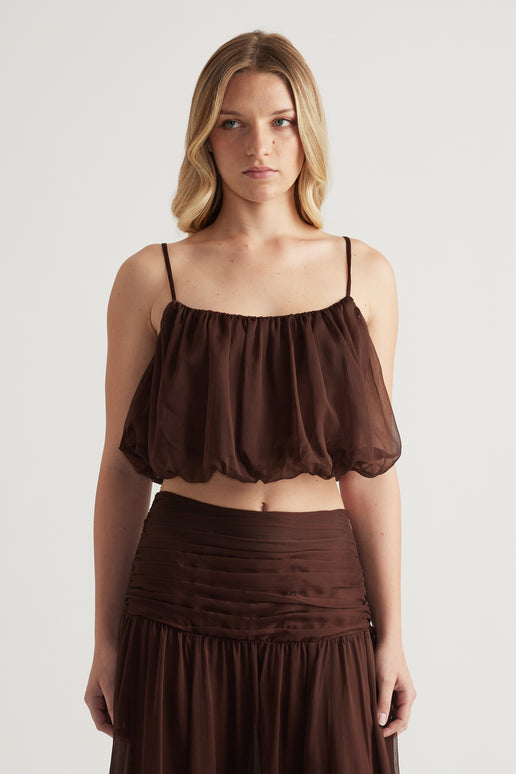 Woman wearing a brown cropped cami with thin adjustable straps and a bubble hem