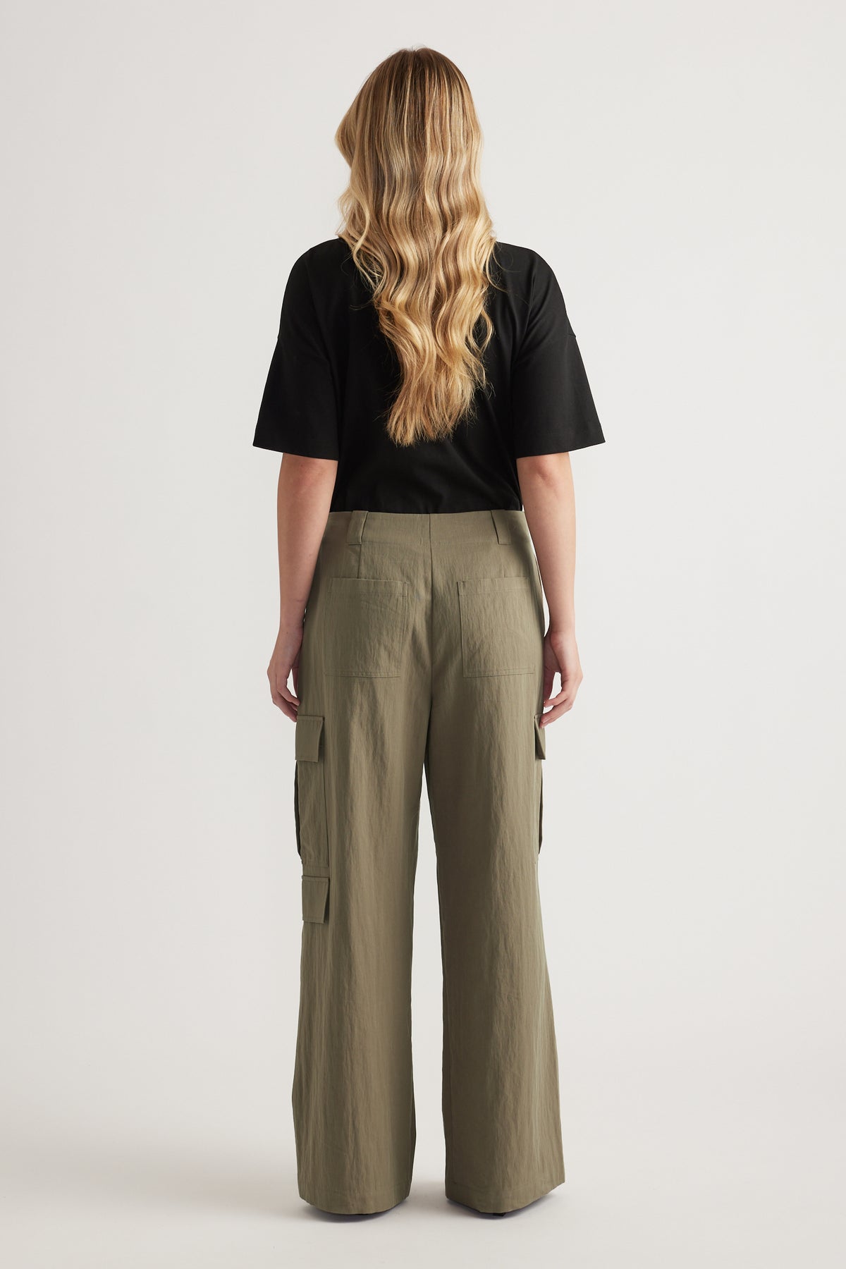 Model wearing olive cargo pants and a black tee shown from the back