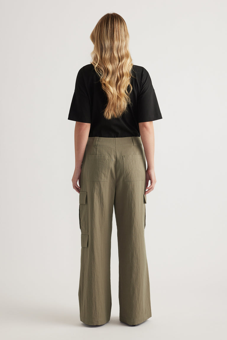 Model wearing olive cargo pants and a black tee shown from the back