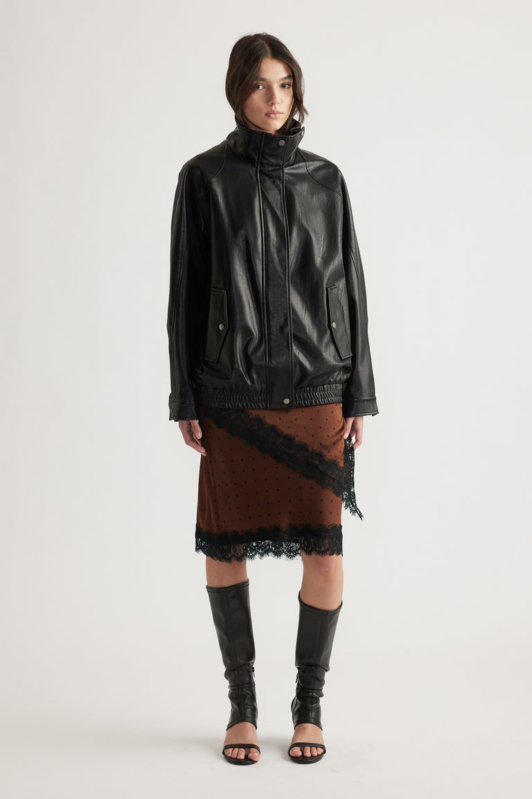 Front view of woman wearing brown midi skirt with black lace trim, paired with black leather jacket and knee-high boots