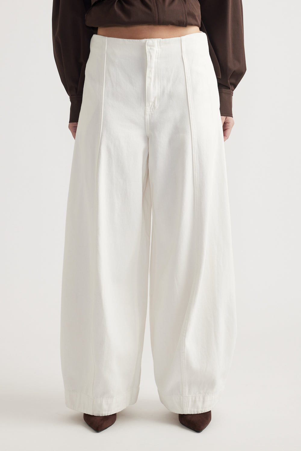 High-waisted white balloon-leg jeans with front seam detailing styled with a dark brown top and pointed boots