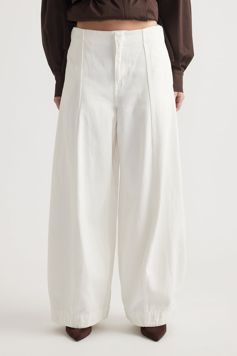 High-waisted white balloon-leg jeans with front seam detailing styled with a dark brown top and pointed boots