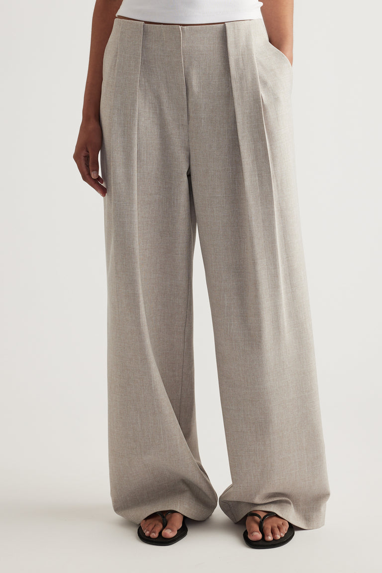 Woman wearing taupe pleated wide-leg pants with side pockets and black sandals
