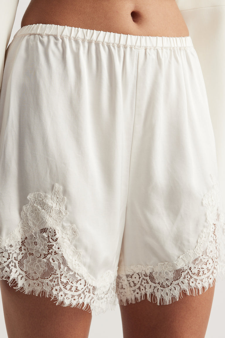 White satin shorts with an elastic waist and delicate lace trim hems