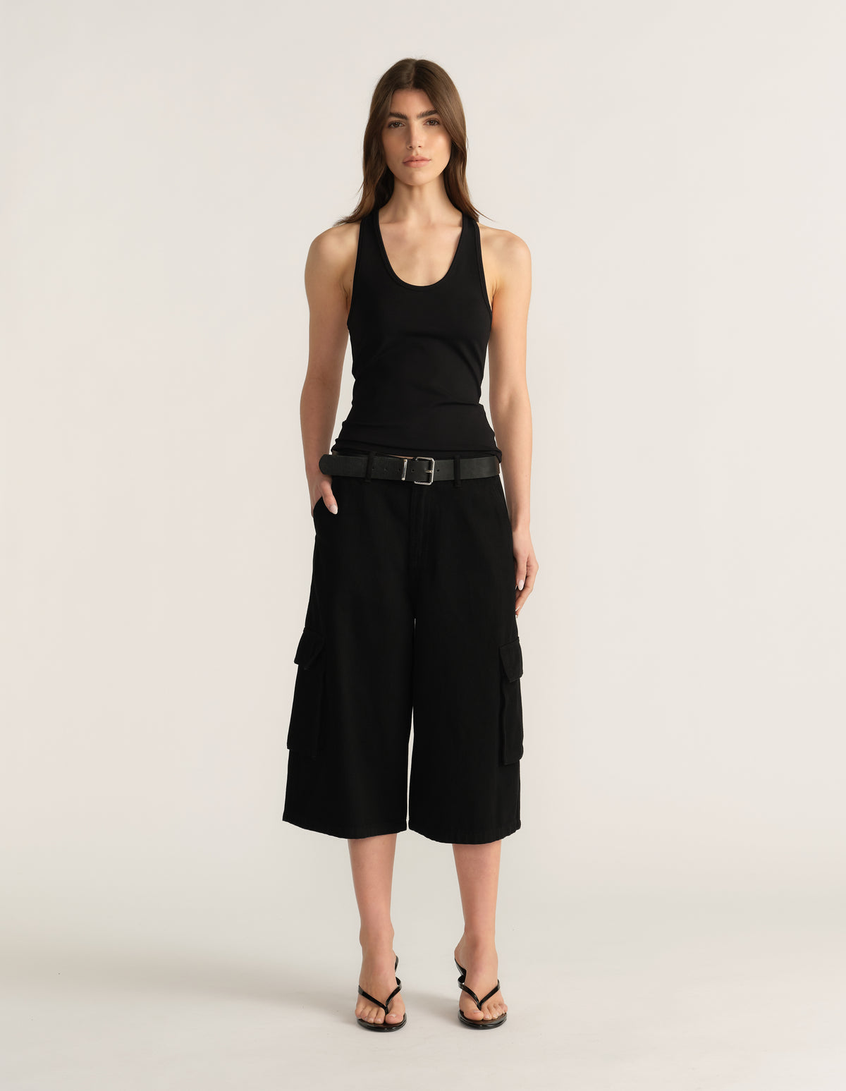 Model wearing black cargo shorts with a tank top, belt and strappy sandals
