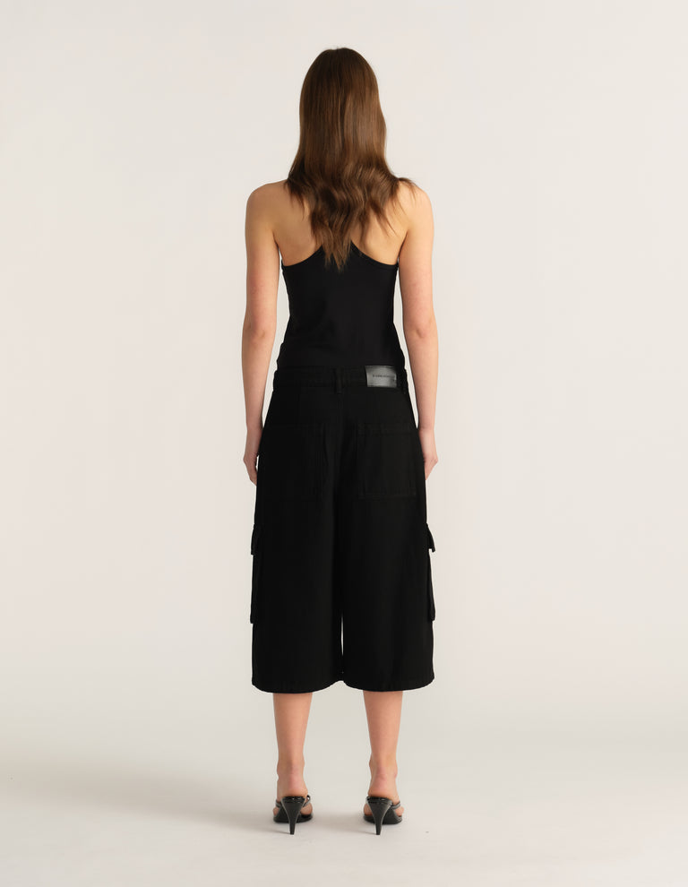 Woman viewed from behind wearing black cargo shorts and a black camisole top