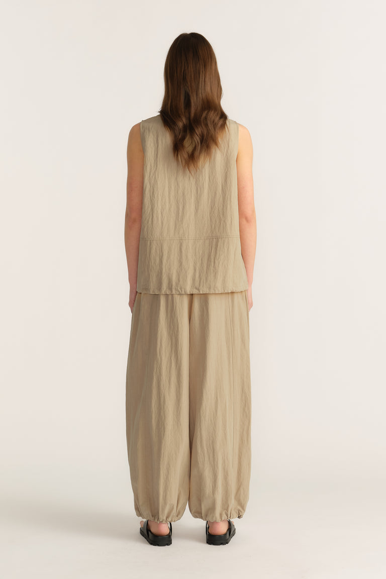 Back view of a woman wearing a beige sleeveless top with wide-leg pants and a relaxed fit