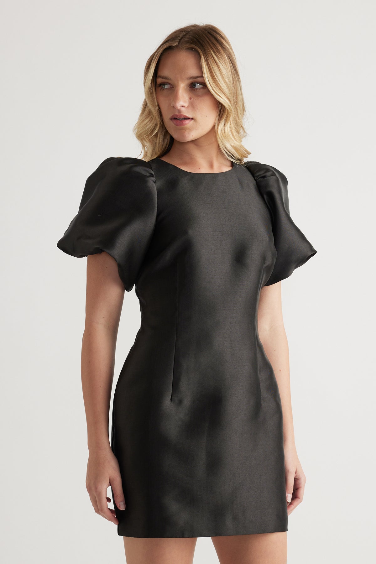 Woman wearing a black mini dress with short puff sleeves and a crew neckline