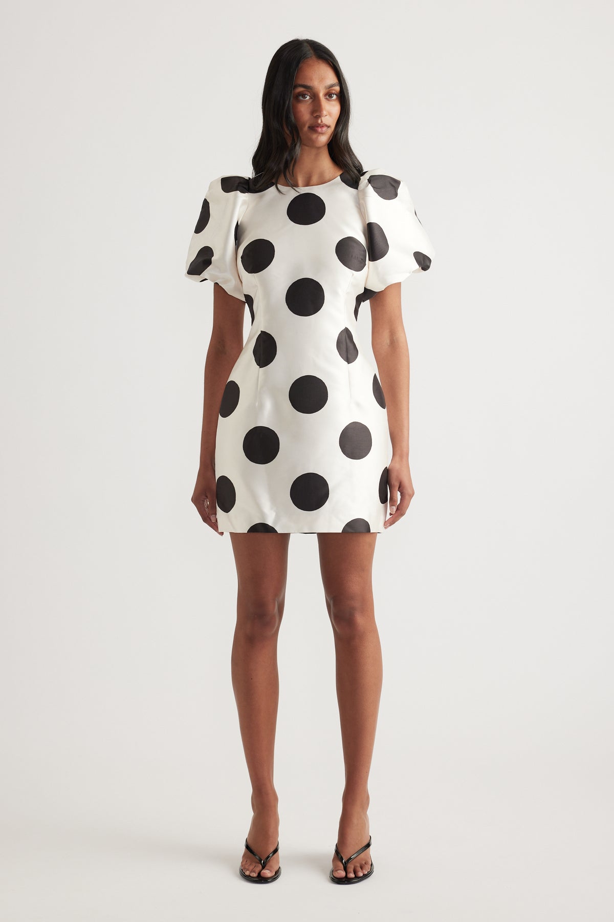 Woman wearing a white mini dress with black polka dots and puff sleeves