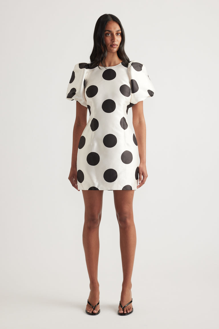 Woman wearing a white mini dress with black polka dots and puff sleeves