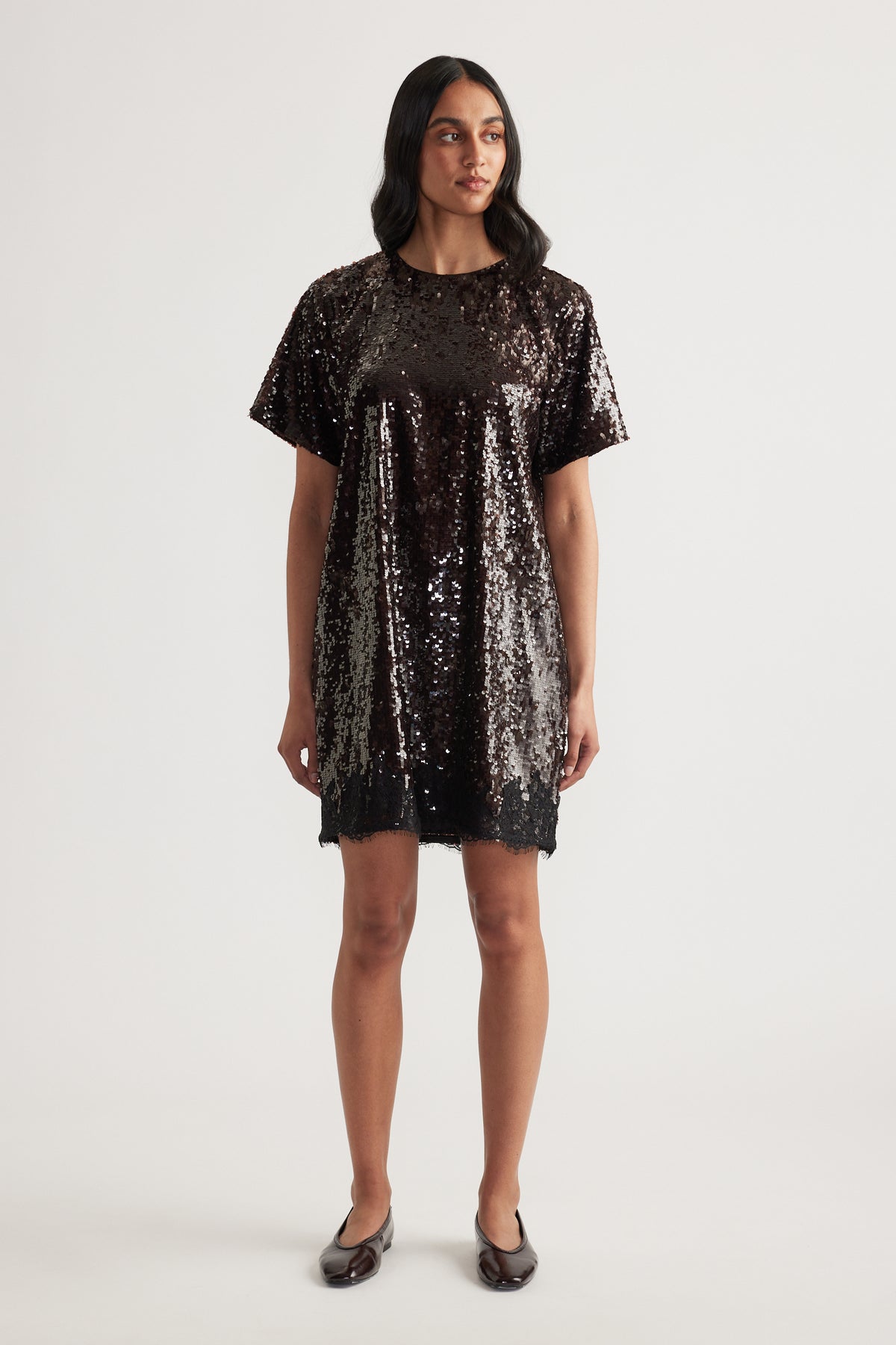 Woman wearing a black sequin mini dress with short sleeves and a crew neck