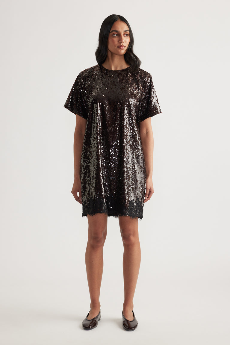 Woman wearing a black sequin mini dress with short sleeves and a crew neck