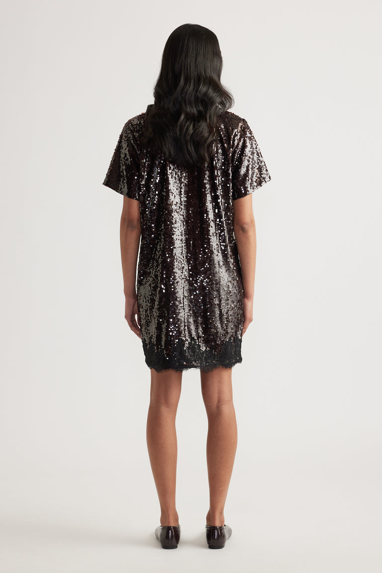 Woman wearing a black sequin short sleeve mini dress with a relaxed fit and scalloped hem