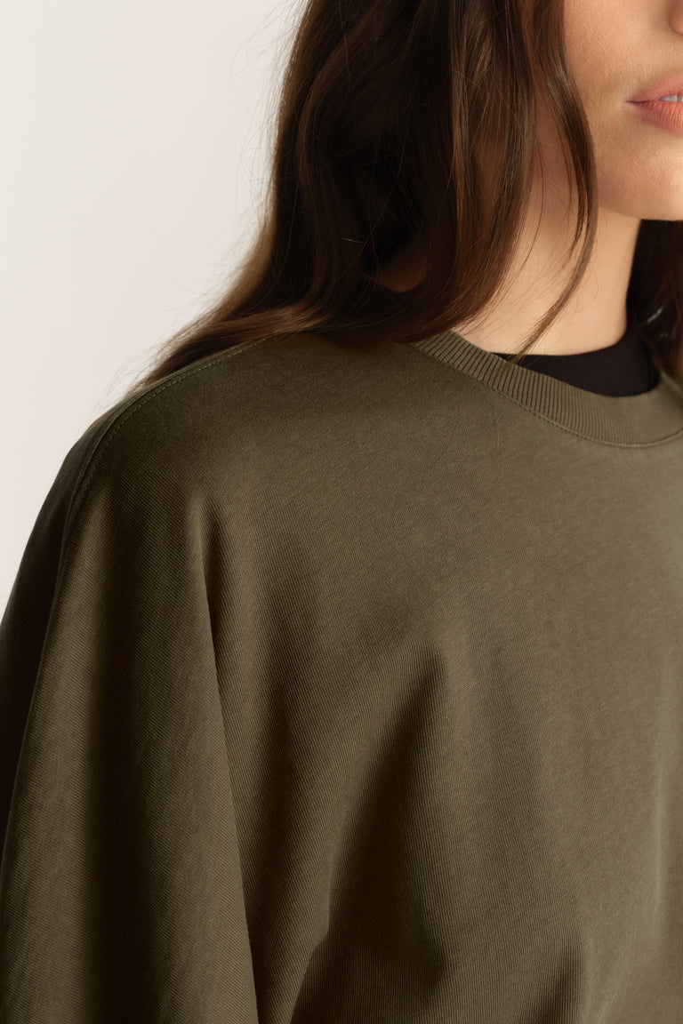 Woman wearing an olive green relaxed fit crew neck tee with drop shoulders and batwing sleeves
