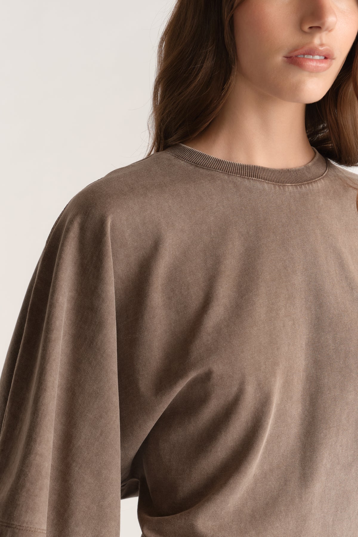 Woman wearing a brown oversized crew neck tee with relaxed batwing sleeves