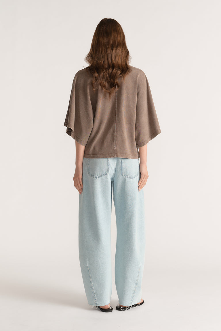 Woman seen from behind wearing a taupe relaxed fit batwing sleeve tee and light wash wide leg jeans