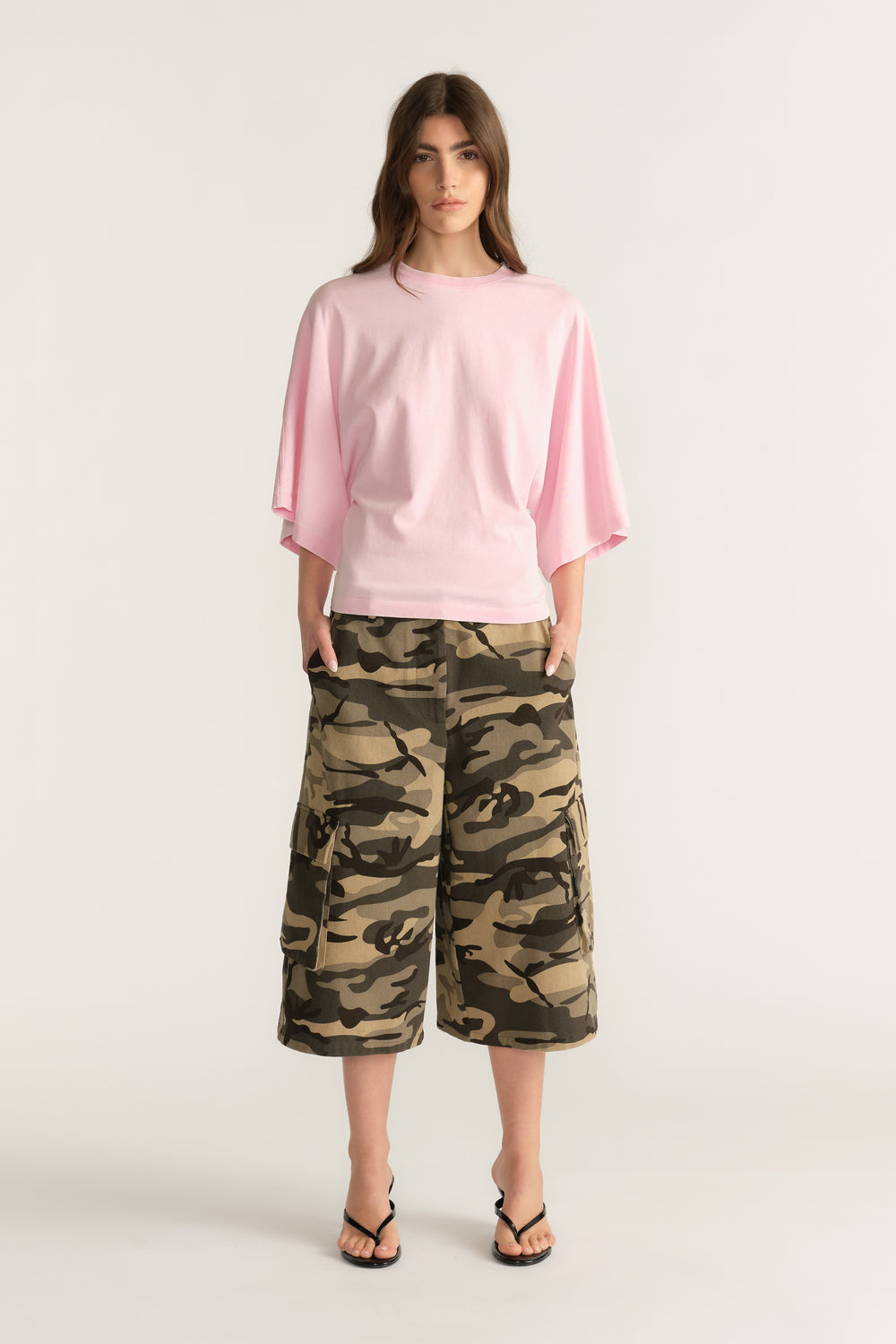 Woman wearing a relaxed pink batwing tee with camouflage knee length shorts and sandals