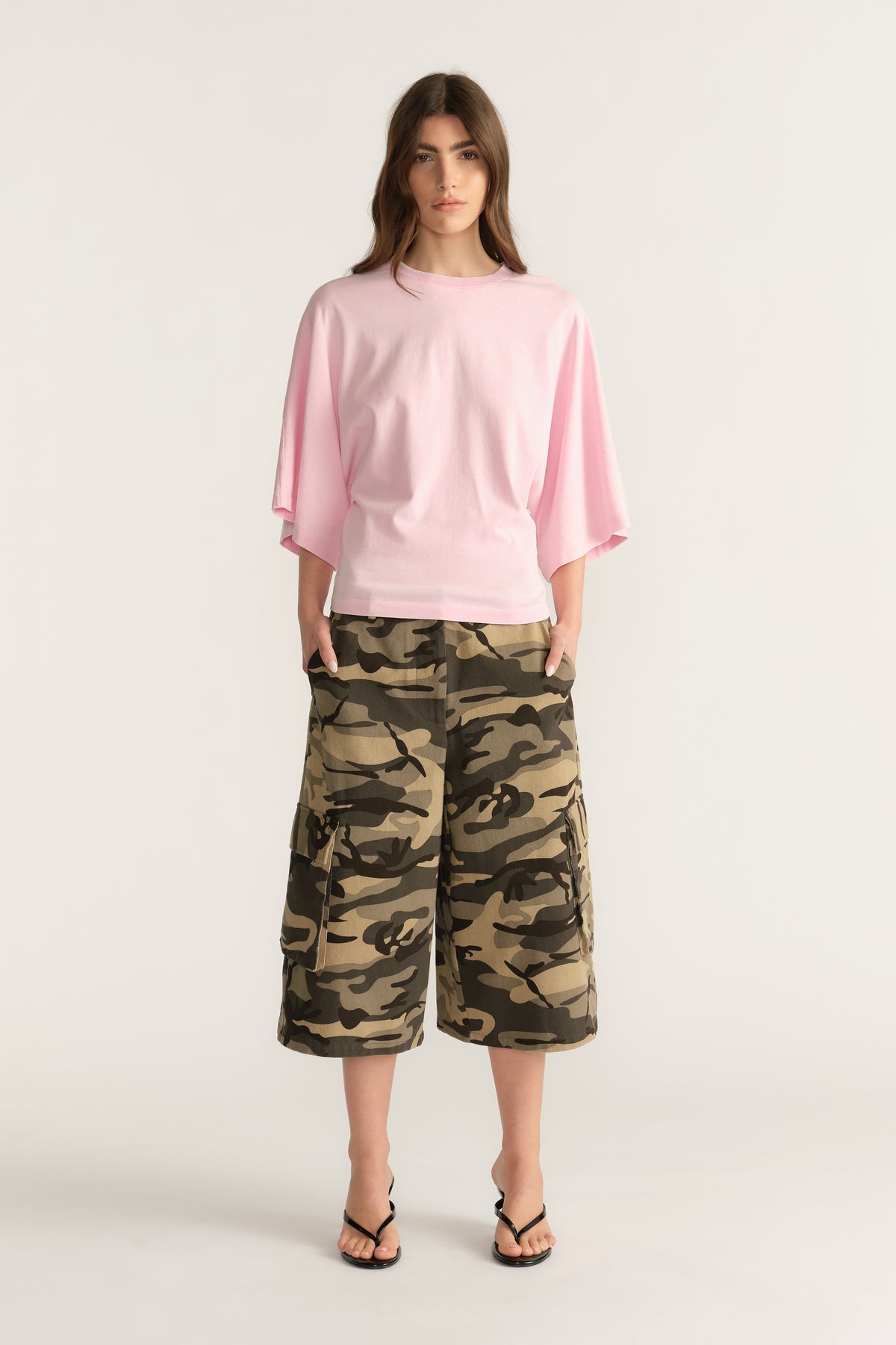 Woman wearing a relaxed pink batwing tee with camouflage knee length shorts and sandals