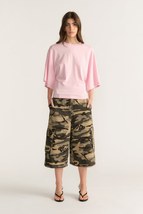 Woman wearing a relaxed pink batwing tee with camouflage knee length shorts and sandals