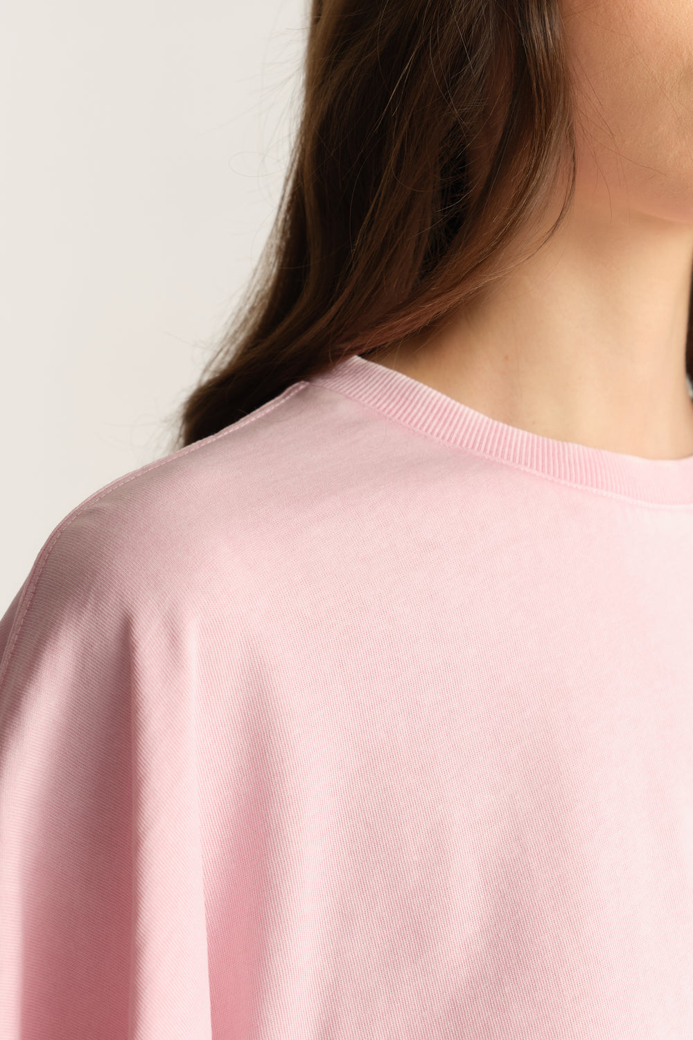 Woman wearing a pale pink relaxed fit tee with a crew neck and batwing sleeves